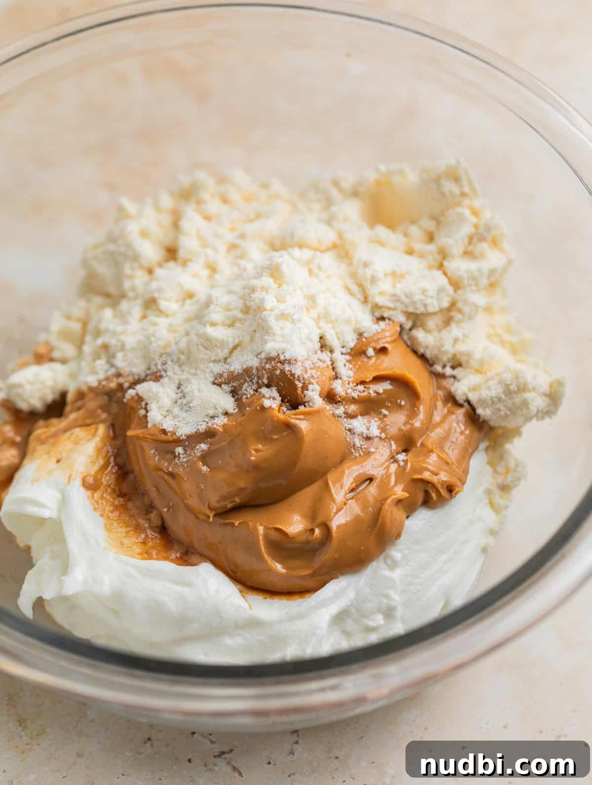 Creamy Greek Yogurt Bark Recipe with Fruit and Honey Toppings 4 Peanut butter, plain Greek yogurt, protein powder and vanilla in glass mixing bowl.