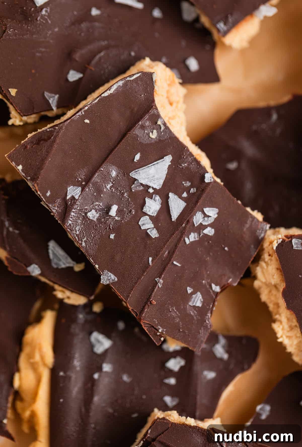 Creamy Greek Yogurt Bark Recipe with Fruit and Honey Toppings 9 Close up of frozen chocolate covered peanut butter yogurt bark scattered on parchment paper.