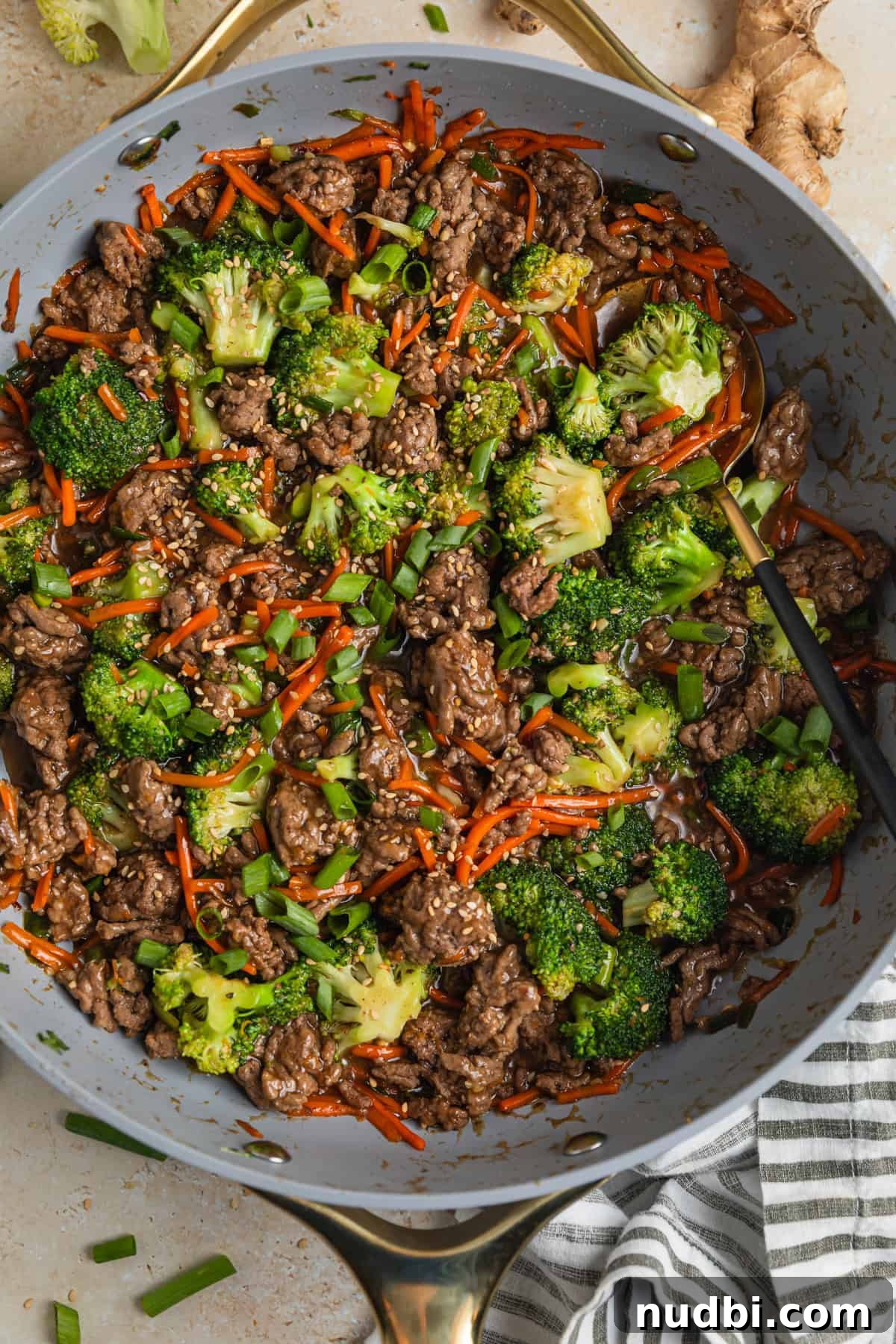 Ground beef teriyaki stir fry prepared in skillet topped with chopped green onions.