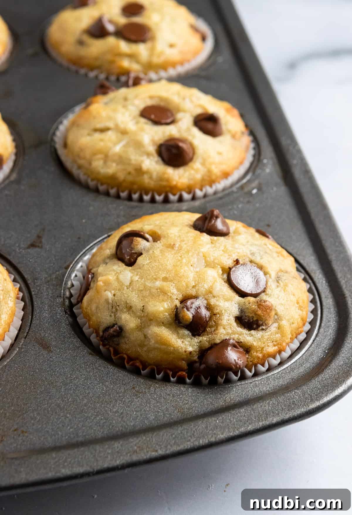 Coconut Banana Muffins with Chocolate Chips That Melt Inside 3 Fresh muffins in muffin tin.