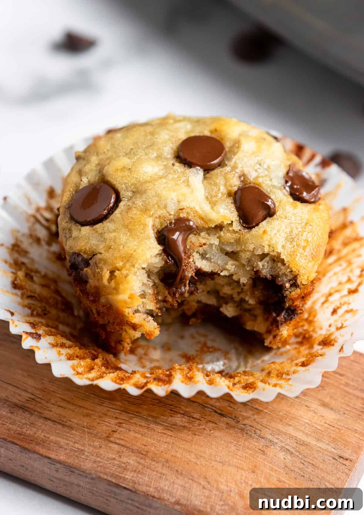 Coconut Banana Muffins with Chocolate Chips That Melt Inside 7 Coconut Banana Muffin with liner pulled off and bite taken.