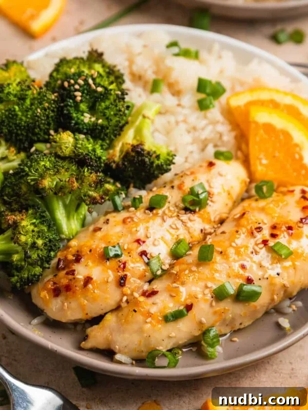 Creamy Skillet Lemon Chicken Recipe for Quick Weeknight Meals 11 Baked orange chicken sheet pan dinner served on plate with white rice and orange slices.