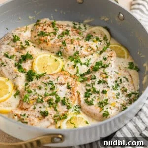 Creamy Skillet Lemon Chicken Recipe for Quick Weeknight Meals 14 Creamy lemon chicken in skillet with lemon slices, cream cheese sauce and chopped parsley over top.