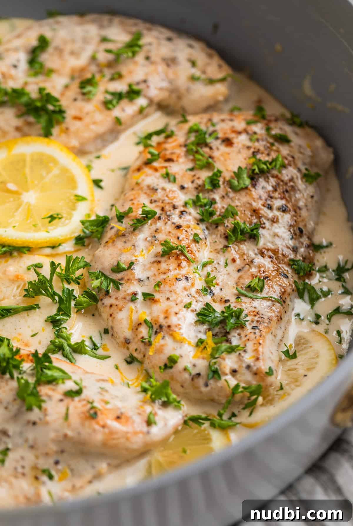 Creamy Skillet Lemon Chicken Recipe for Quick Weeknight Meals 8 Pan with chicken topped with cream sauce with lemon slices and fresh parsley.