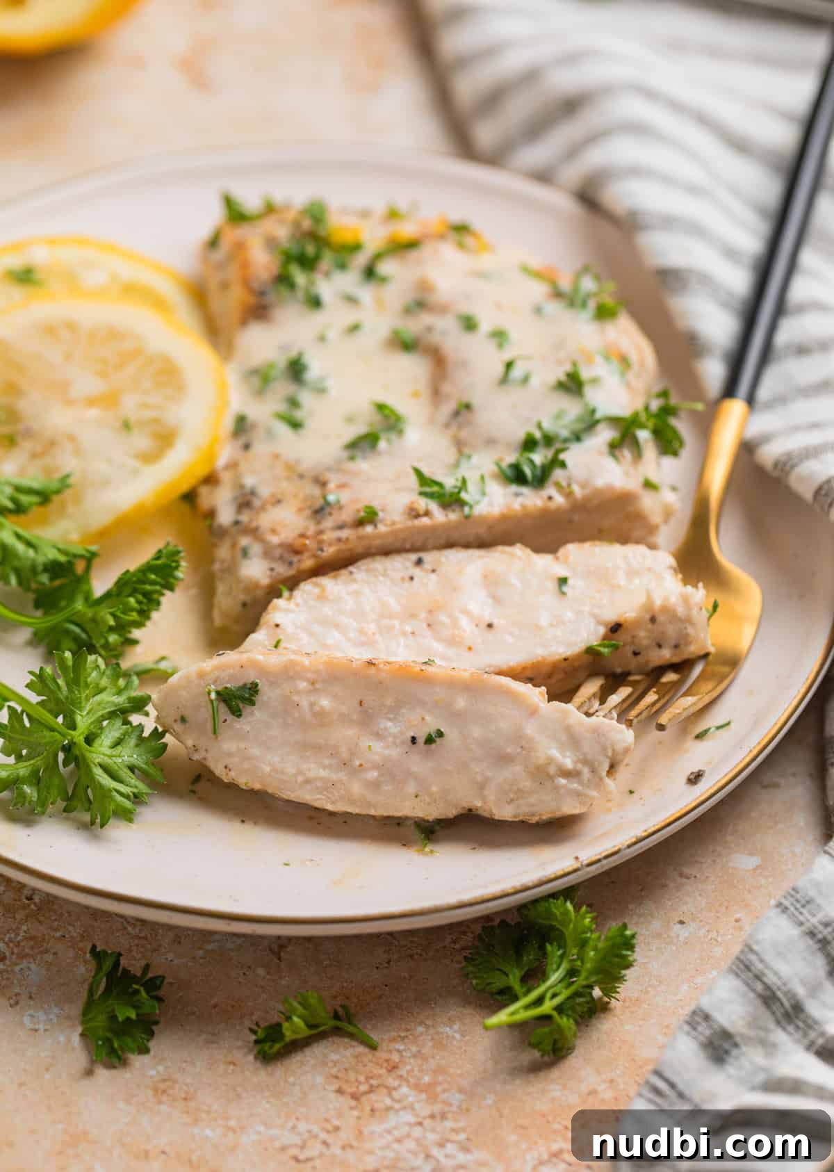 Creamy Skillet Lemon Chicken Recipe for Quick Weeknight Meals 9 Sliced chicken breast on plate with lemon slices and parsley beside it.