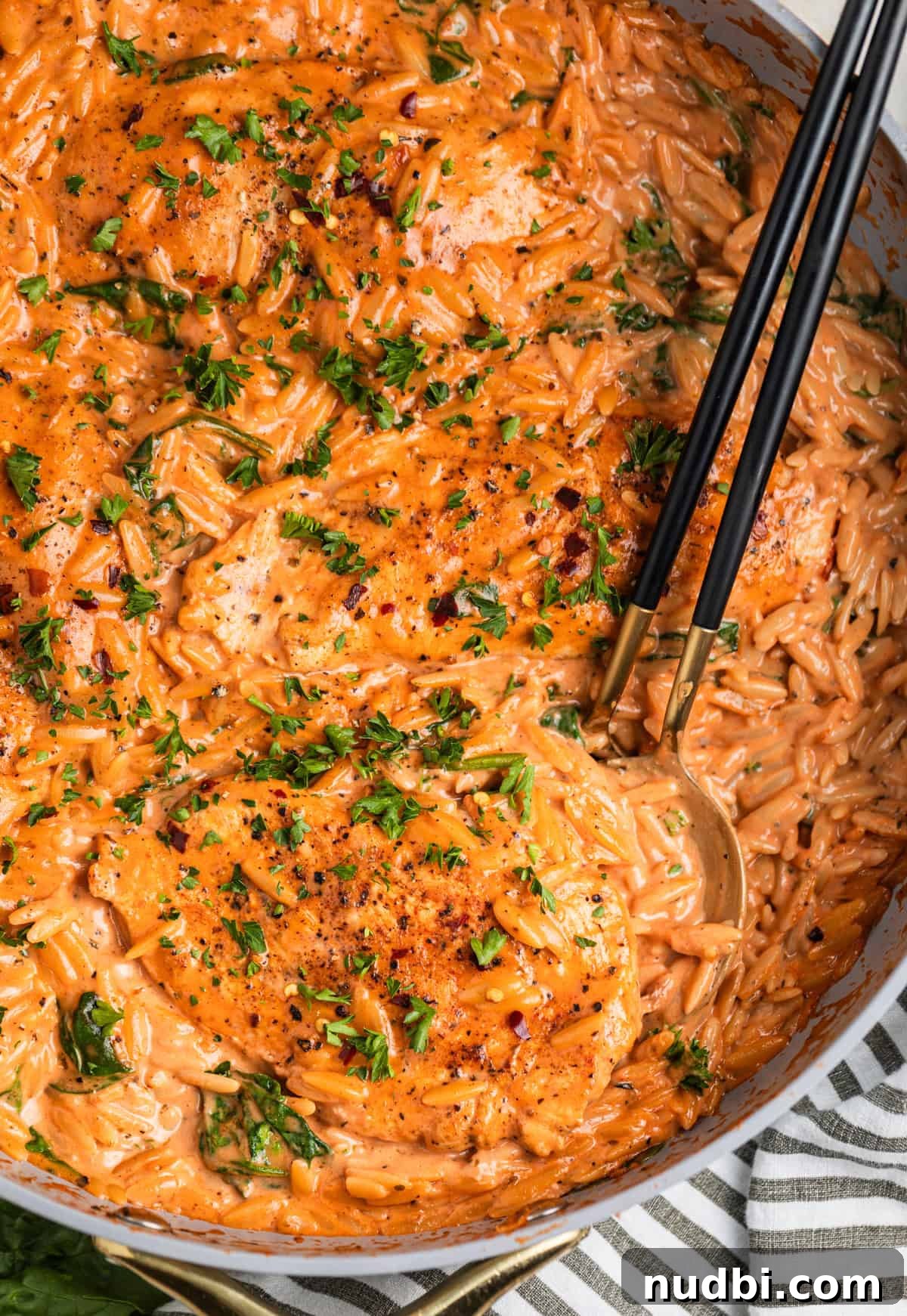 Creamy Chicken Orzo Skillet with Garlic and Parmesan 3 Overhead view of skillet with creamy tomato pasta and chicken topped with parsley.