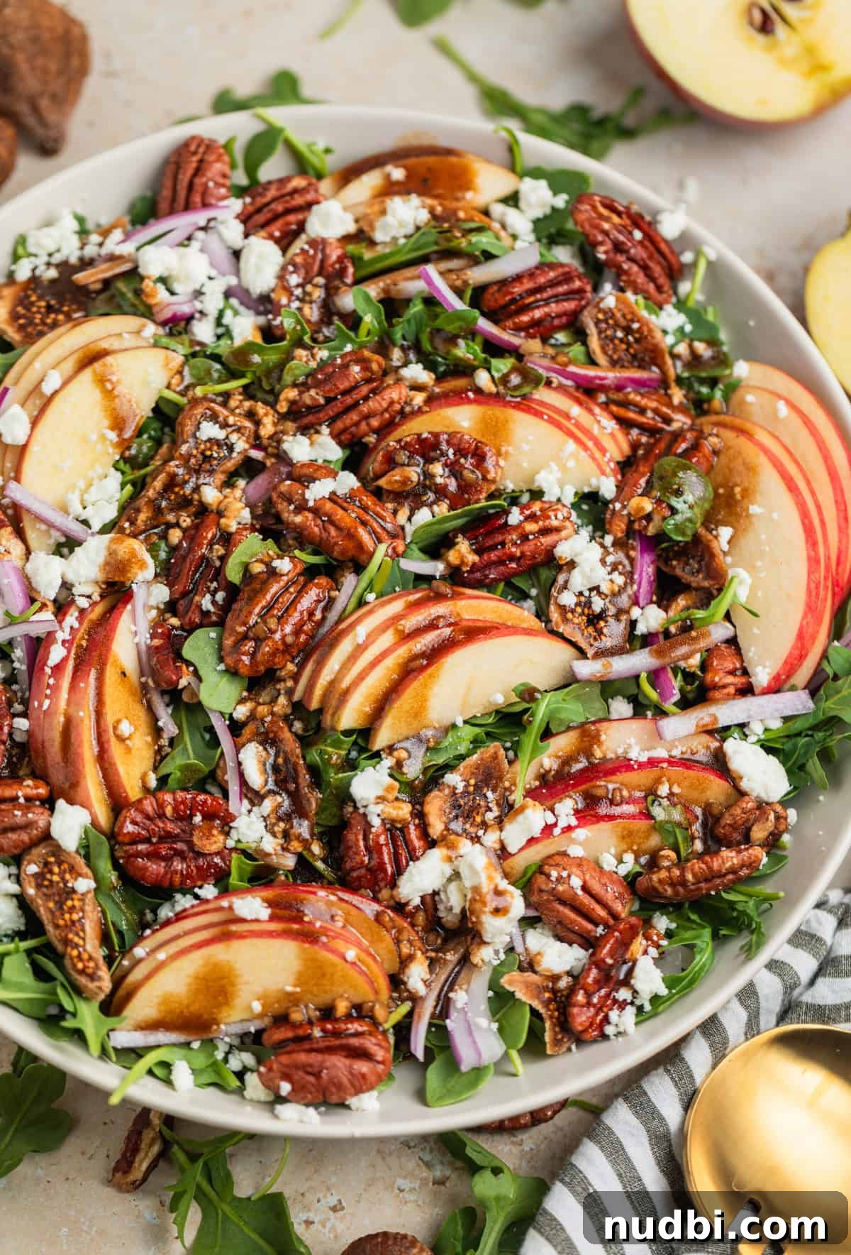 Crisp Apple and Arugula Salad with Honey Dijon Dressing 2 Salad bowl with arugula, sliced apples, goat cheese crumbles, onion and pecans topped with dressing.