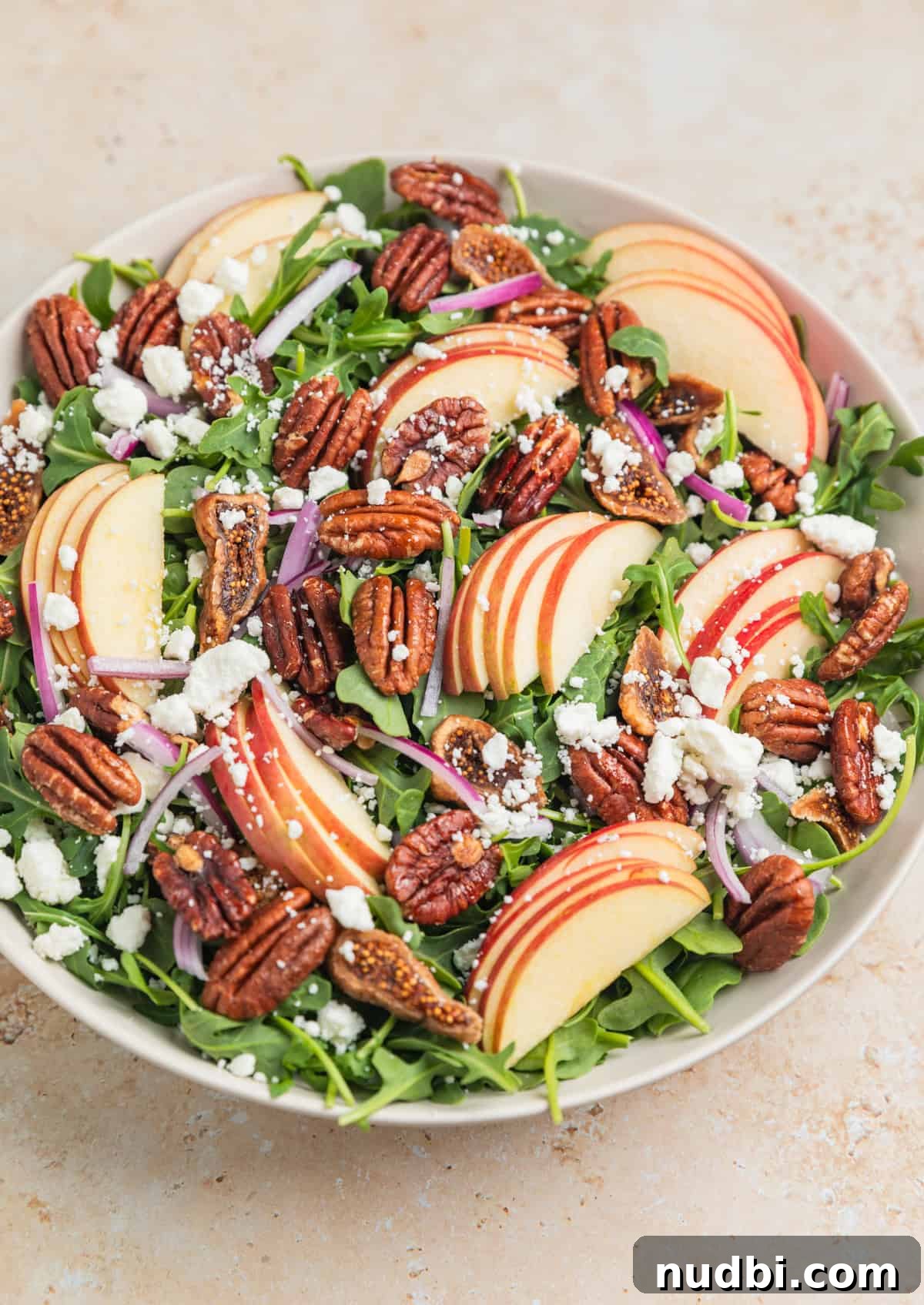 Crisp Apple and Arugula Salad with Honey Dijon Dressing 7 Salad bowl with baby arugula, sliced apples, figs, onion, pecans and other ingredients before dressing added.