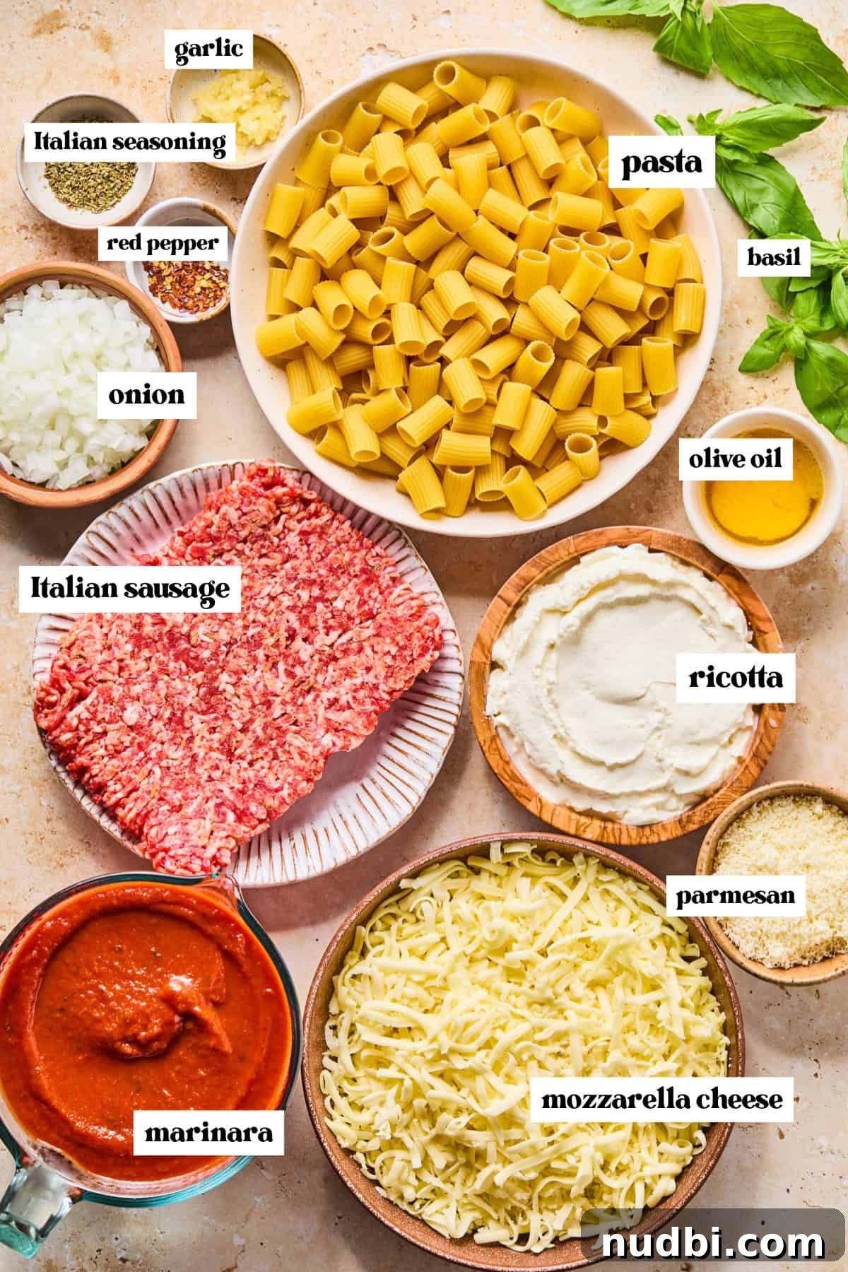 Cheesy Italian Sausage Pasta Bake with Roasted Tomatoes 4 Pasta, meat, basil and other ingredients arranged on surface prepped for recipe.