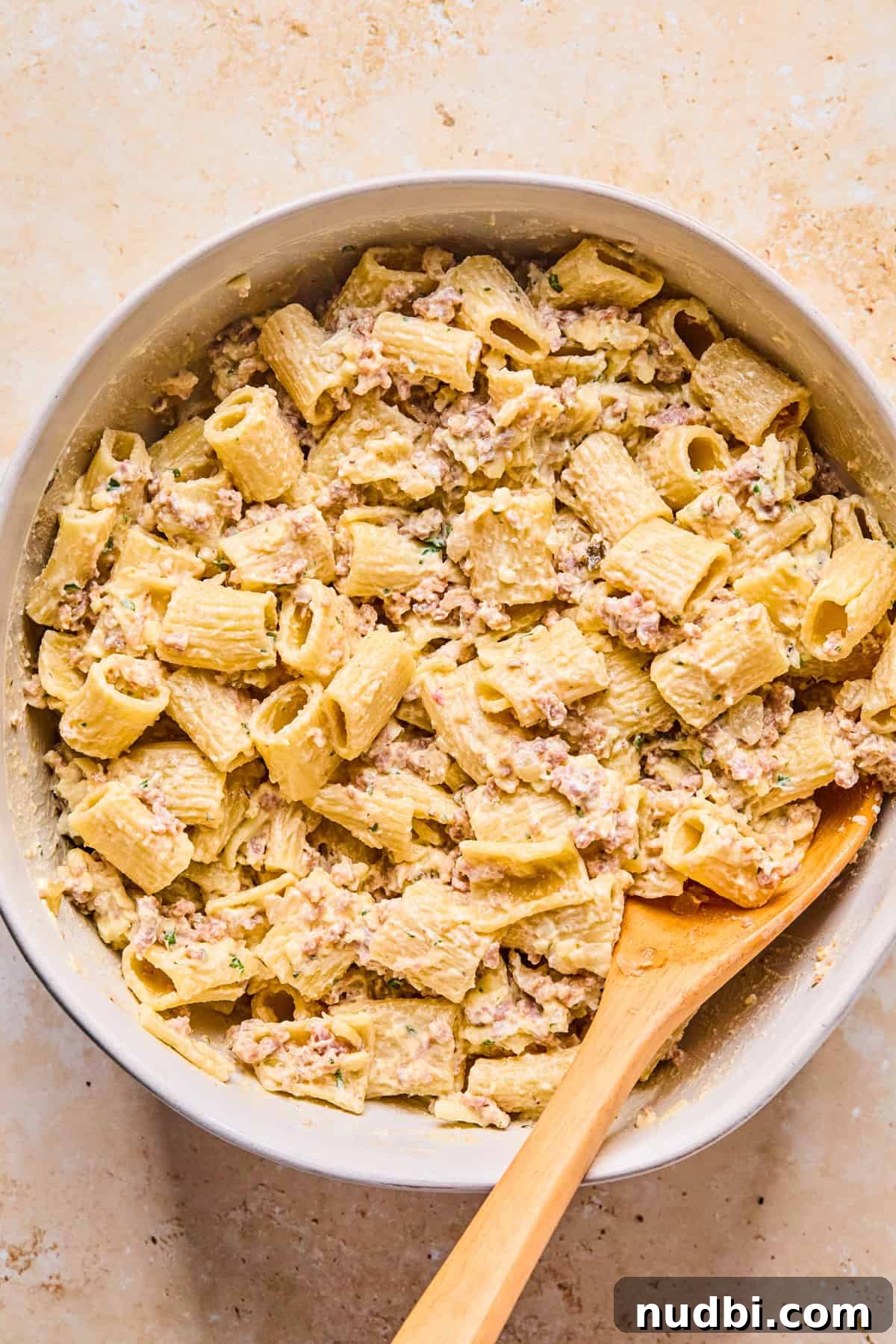 Cheesy Italian Sausage Pasta Bake with Roasted Tomatoes 9 Meat and pasta added to cheese mixture in bowl.