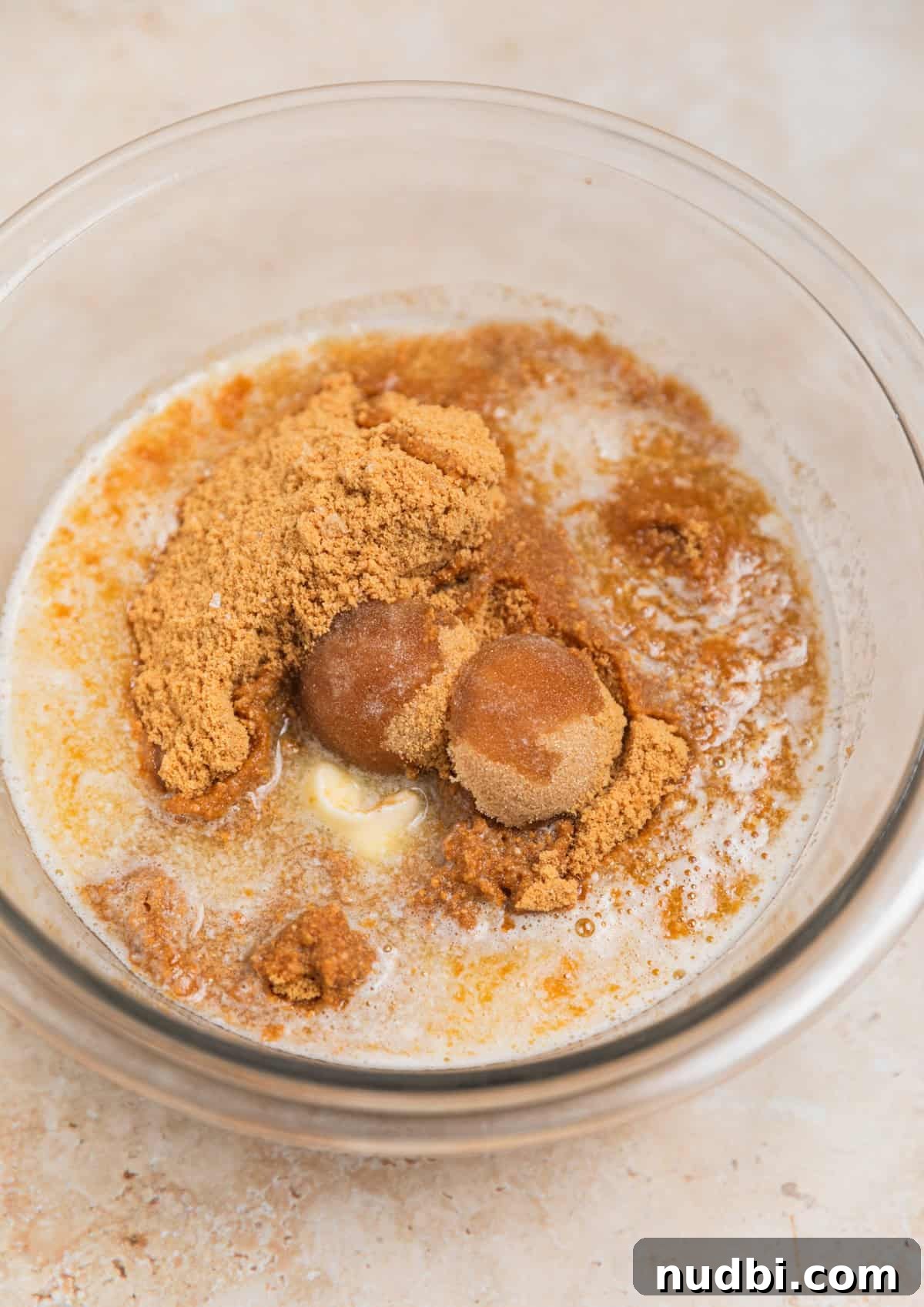 No-Bake Pumpkin Cheesecake Bars Recipe — Creamy Autumn Dessert 5 Brown sugar and melted butter in glass bowl with cookie crumbs.