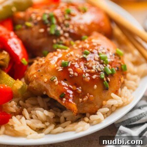 Honey garlic chicken thighs over rice with sliced bell peppers and chopsticks.