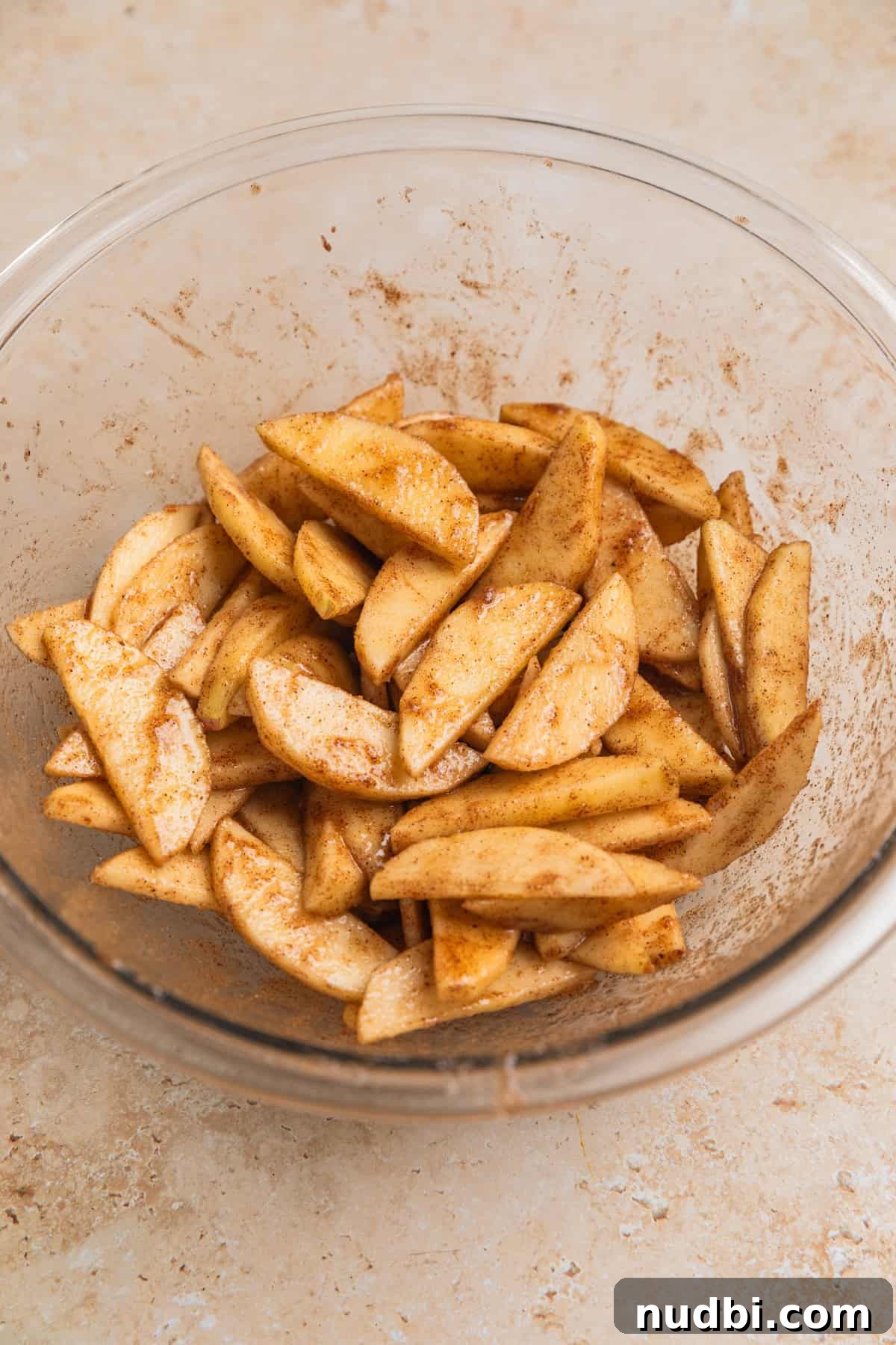 Crisp Puff Pastry Apple Tart Recipe for Homemade Dessert 4 Apple slices tossed in cinnamon and sugar in glass bowl.