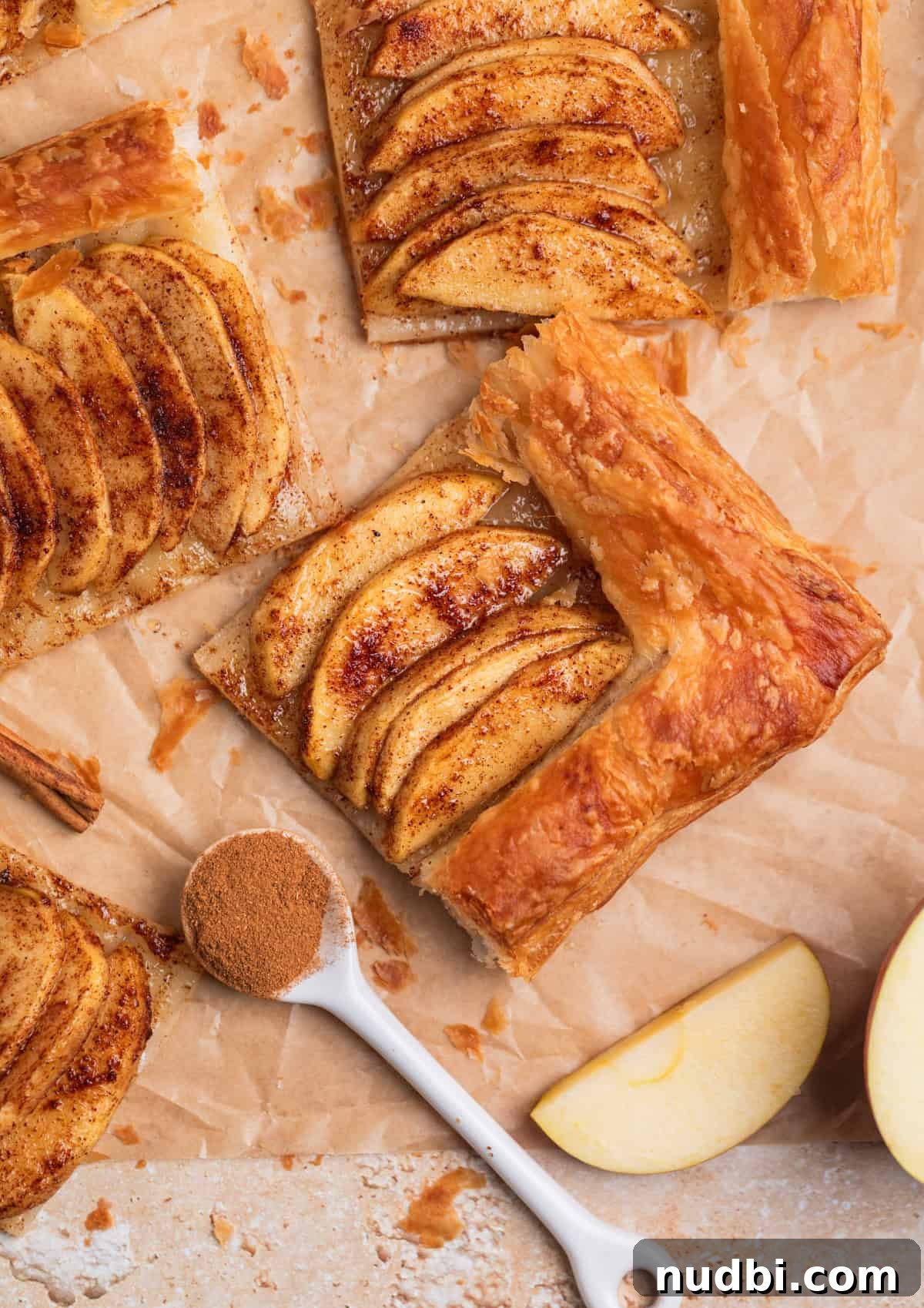 Crisp Puff Pastry Apple Tart Recipe for Homemade Dessert 7 Puff pastry cinnamon apple tarts arranged on parchment.