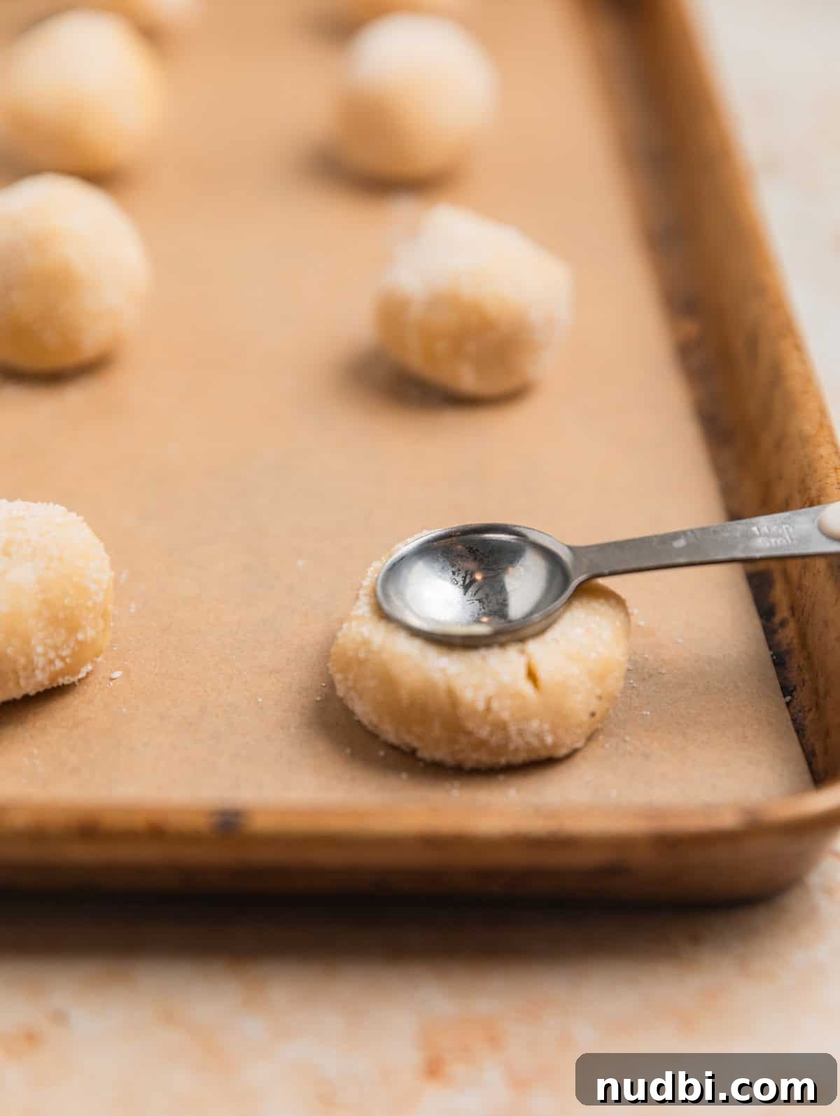 Nutella Thumbprint Cookies Recipe — Gooey Chocolate Hazelnut Treats 9 Teaspoon pressing into cookie dough ball to make a thumbprint like impression.