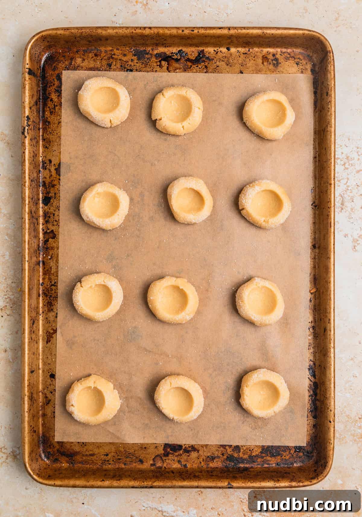 Nutella Thumbprint Cookies Recipe — Gooey Chocolate Hazelnut Treats 10 Thumbprint cookie dough arranged on parchment lined cookie sheet.