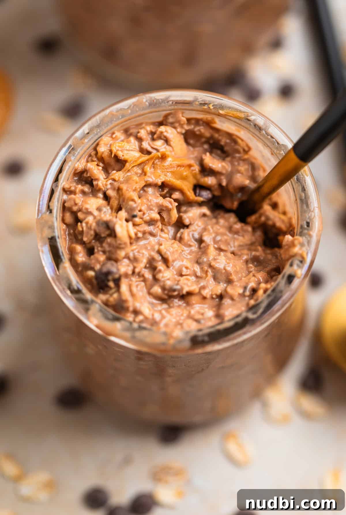 Chocolate Peanut Butter Overnight Oats Recipe for Creamy Breakfast 2 Spoon scooping into chocolate peanut butter overnight oats in glass jar.