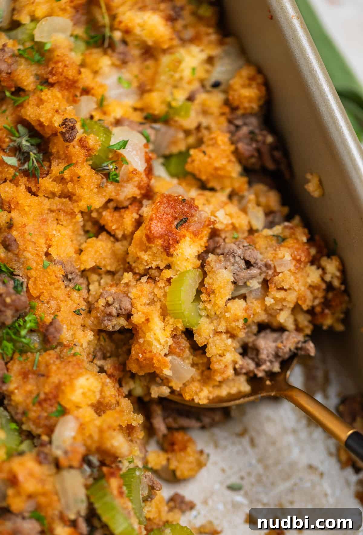 Savory Beef and Cornbread Stuffing Recipe for Holiday Dinners 2 Corn bread and ground beef stuffing in pan with serving spoon scooping into it.