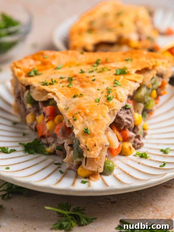 Savory Beef and Cornbread Stuffing Recipe for Holiday Dinners 10 Slice of beef pot pie on plate topped with chopped parsley.