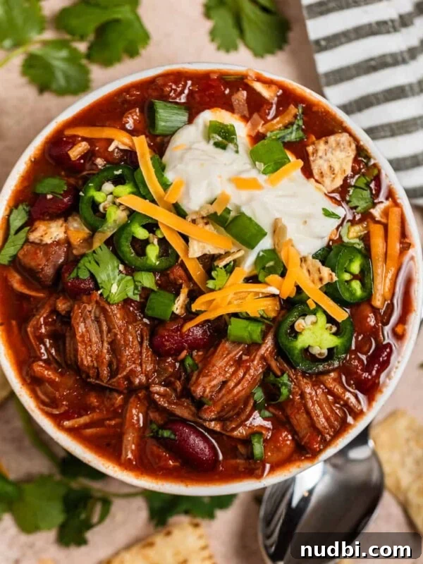 Savory Beef and Cornbread Stuffing Recipe for Holiday Dinners 11 Overhead view of shredded beef chili topped with sour cream, cilantro, cheese and more.