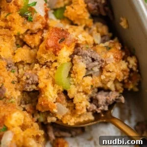 Savory Beef and Cornbread Stuffing Recipe for Holiday Dinners 13 Serving spoon with scoop of cornbread stuffing with ground beef, celery, and fresh herbs.