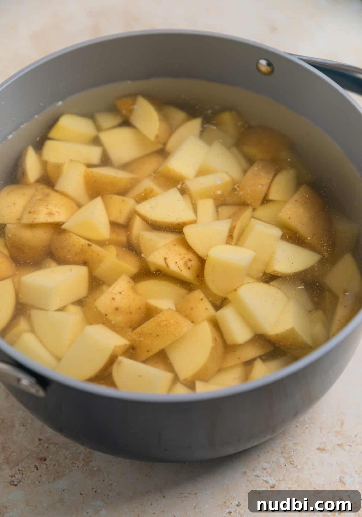 Creamy Boursin Mashed Potatoes Recipe for Garlic-Herb Flavor 3 Water in pot covering quartered yukon gold potatoes.