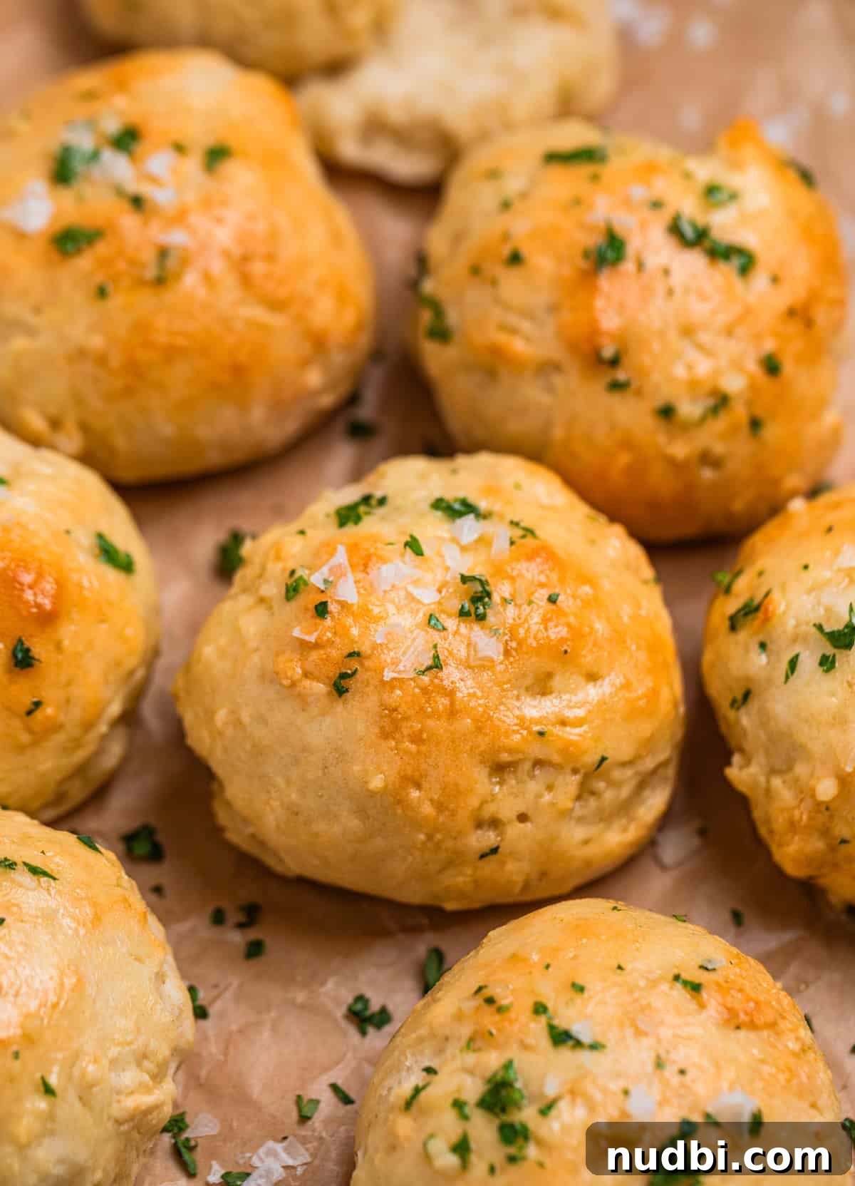 Quick No-Yeast Dinner Rolls Recipe for Soft, Fast Bread 2 No yeast dinner rolls topped with garlic butter, flaked sea salt and parsley on parchment.