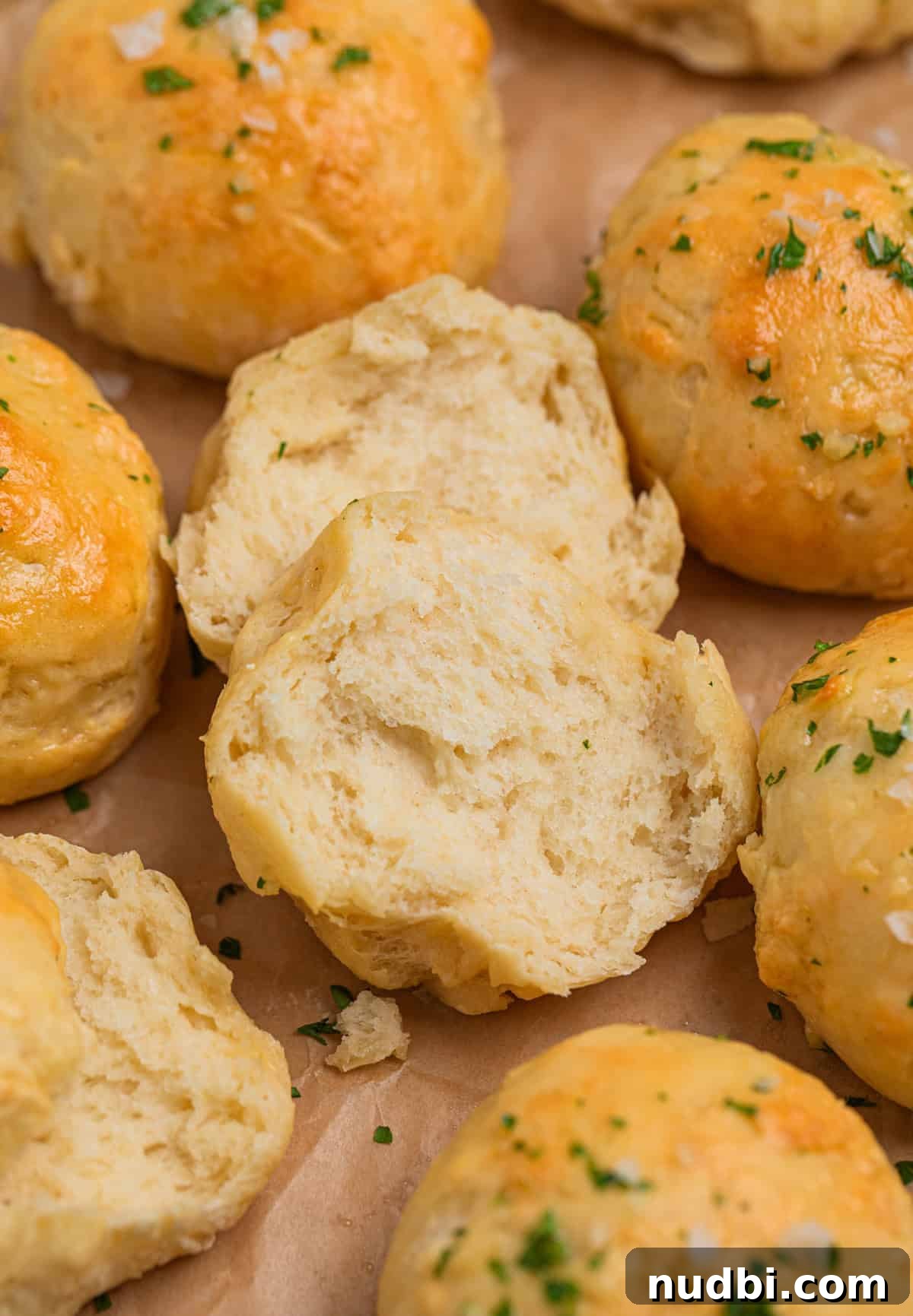 Quick No-Yeast Dinner Rolls Recipe for Soft, Fast Bread 12 Dinner rolls on parchment with one broken apart to show texture.