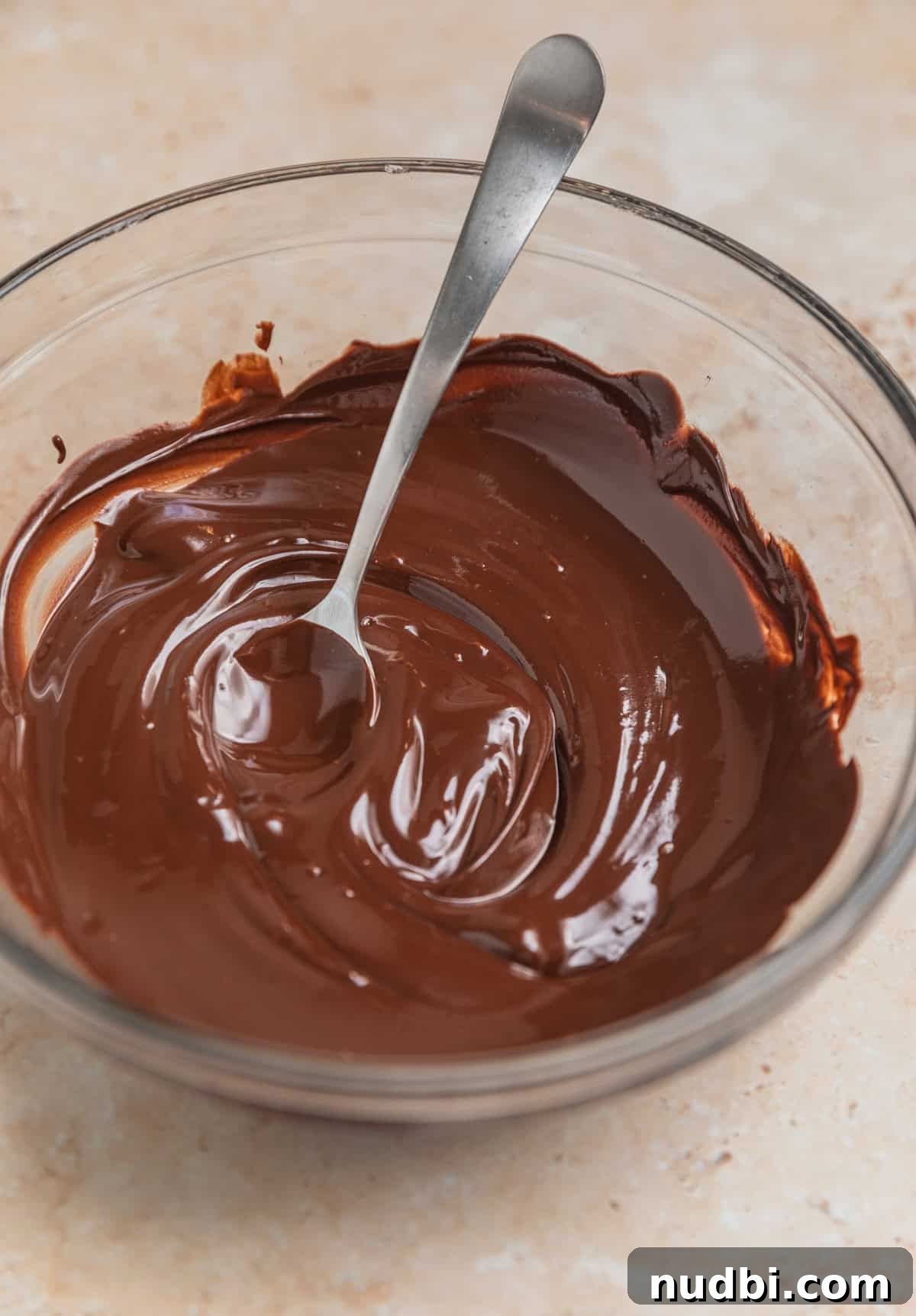 Peppermint Bark Brownies Recipe: Fudgy Chocolate Mint Bars 5 Melted chocolate in bowl with spoon.