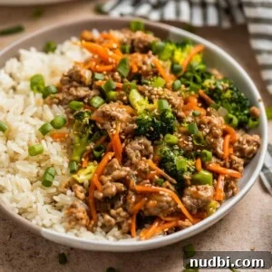 Turkey stir fry served with rice and topped with sesame seeds and green onion.