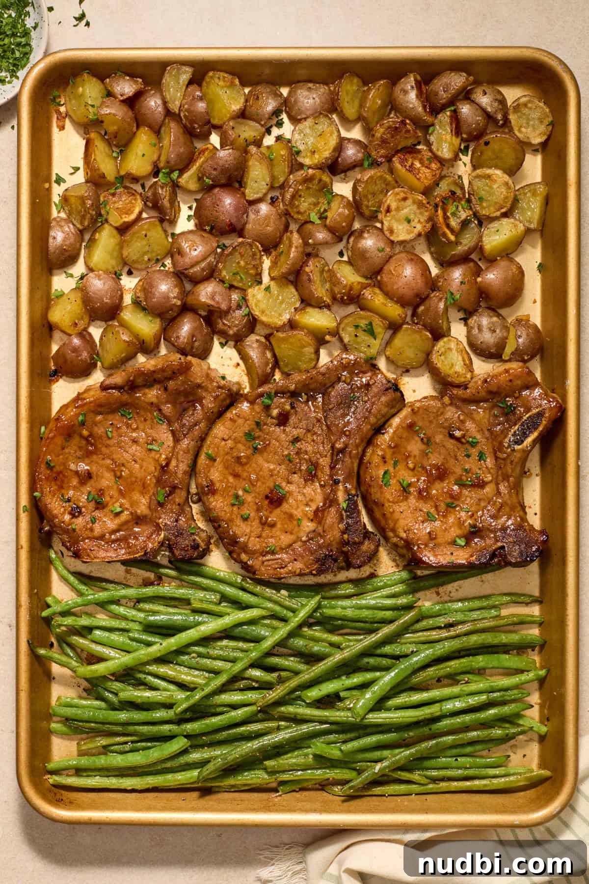 Crispy Sheet Pan Pork Chops with Roasted Vegetables 2 Sheet pan pork chops with parmesan potatoes and green beans on pan.