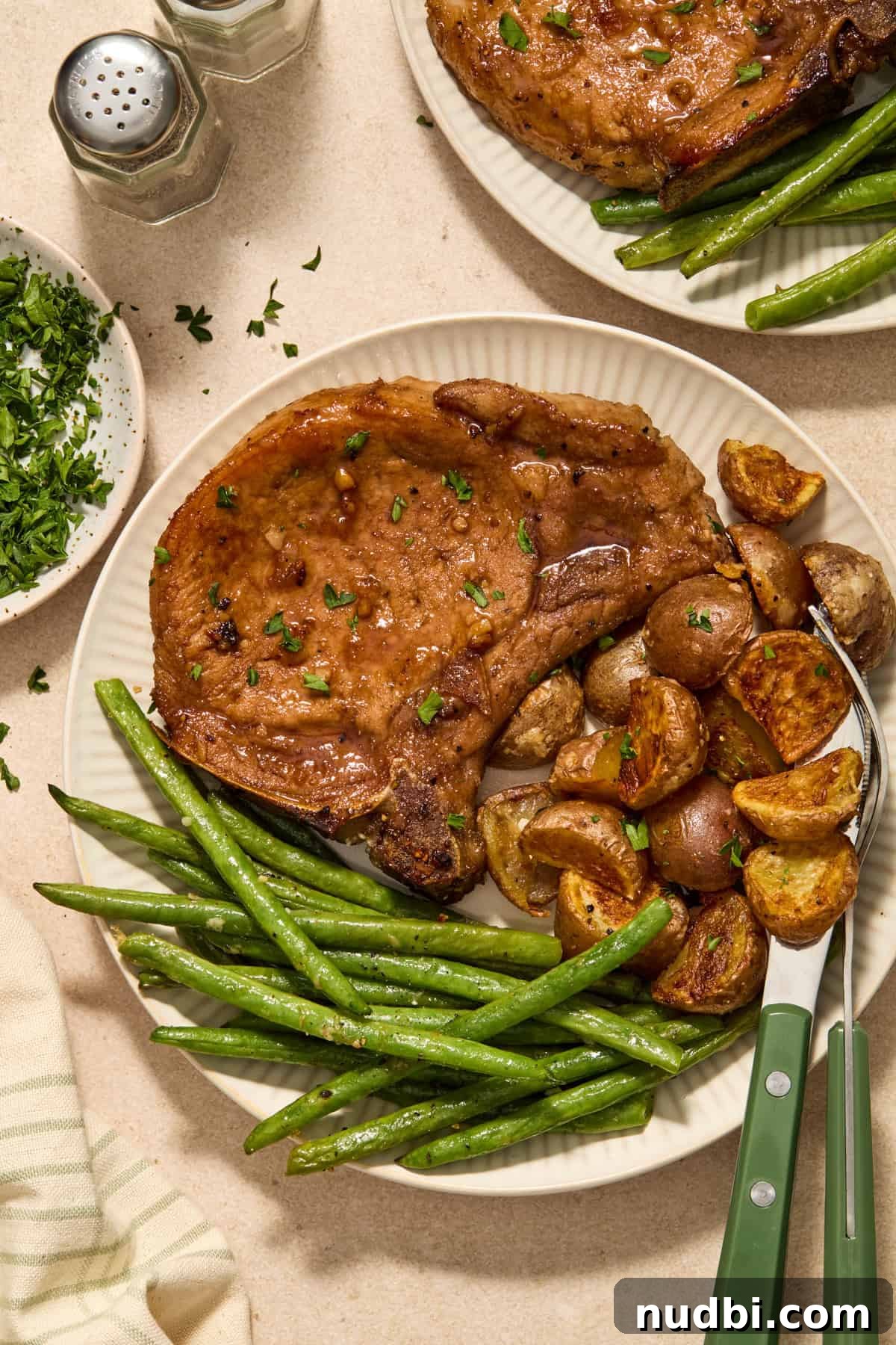 Crispy Sheet Pan Pork Chops with Roasted Vegetables 11 Plate with honey garlic pork chops, green beans and potatoes.