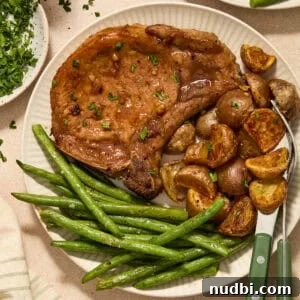 Crispy Sheet Pan Pork Chops with Roasted Vegetables 12 Sheet pan pork chops served on plate with potatoes and green beans.