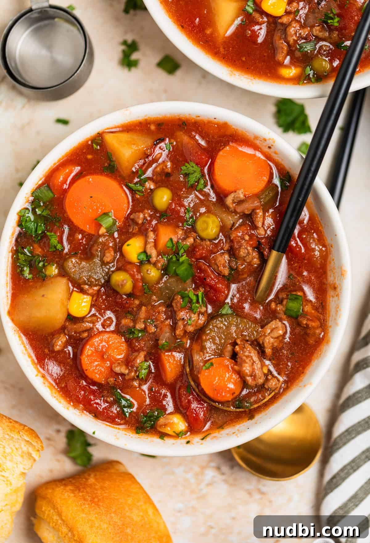 Slow Cooker Hamburger Soup Recipe for Hearty Weeknight Meals 9 Bowl of hamburger soup with vegetables with spoon scooping into it.