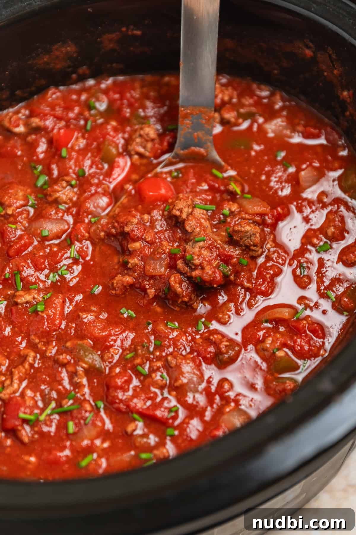 Hearty No-Bean Slow Cooker Chili Recipe 2 Crock pot with beef chili with no beans with ladle scooping into the pot.