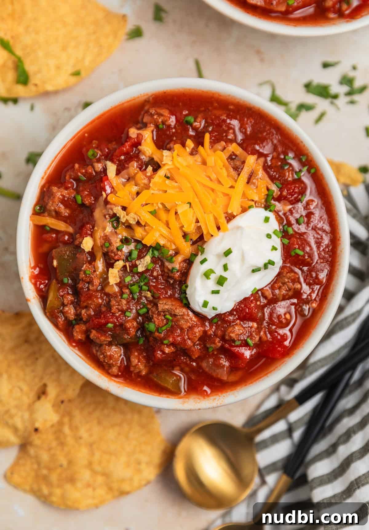 Hearty No-Bean Slow Cooker Chili Recipe 8 Overhead view of bowl of chili with sour cream and shredded cheese over top.