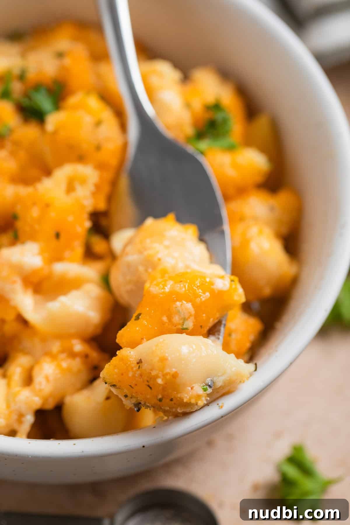 High-Protein Mac and Cheese Recipe for Muscle Gain 3 Forkful of macaroni in cheese propped on edge of bowl.