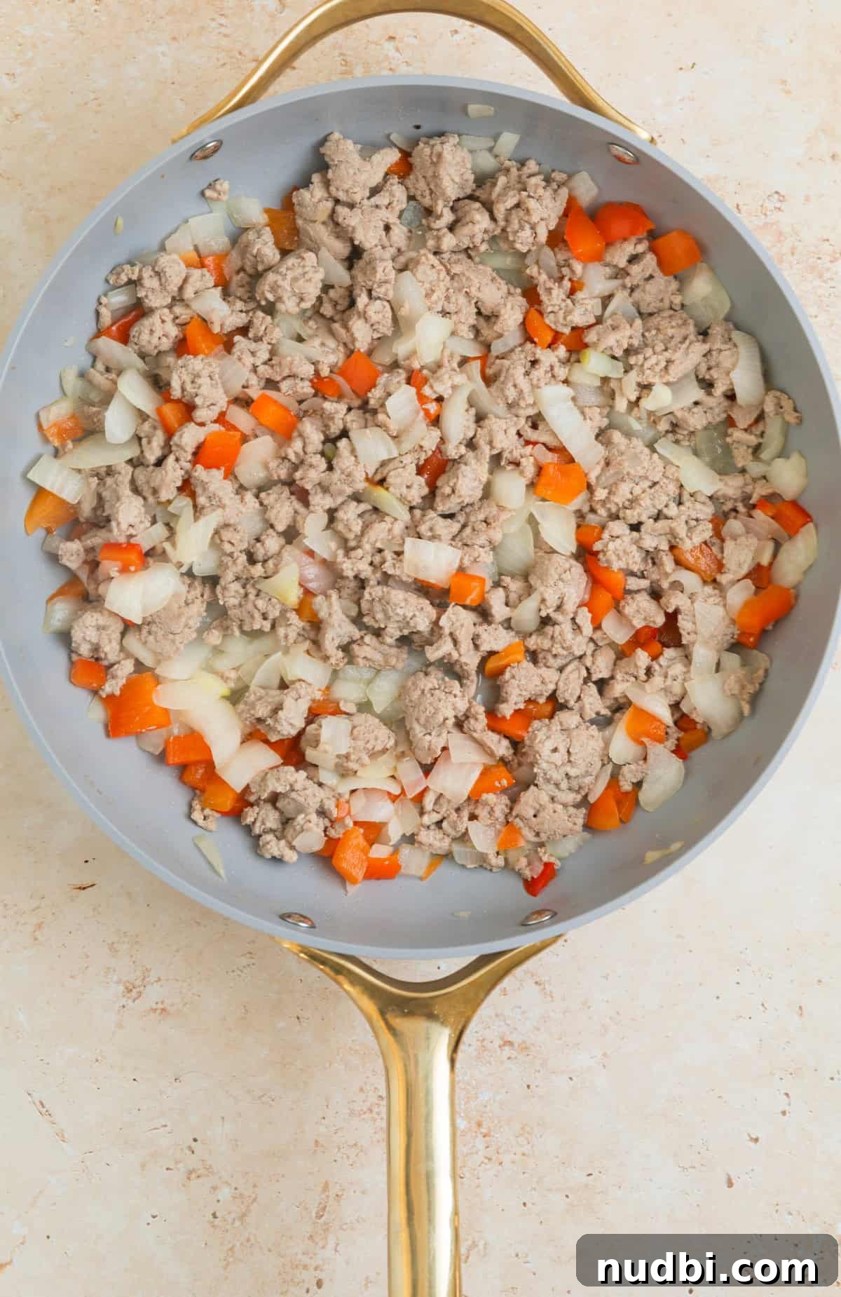 Skillet Ravioli Lasagna Recipe: Quick One-Pan Italian Dinner 6 Browned ground turkey with red bell pepper and onion in skillet.