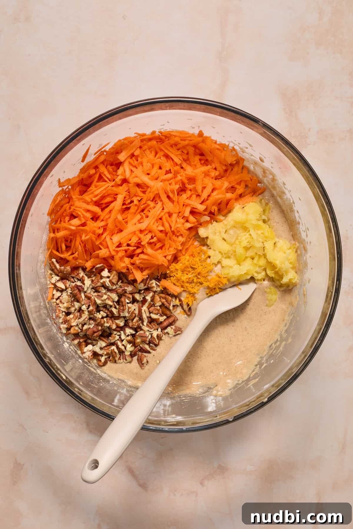 Moist Carrot Cake Recipe Using Cake Mix 6 Shredded carrots, pecans and pineapple in bowl of cake batter before stirring.