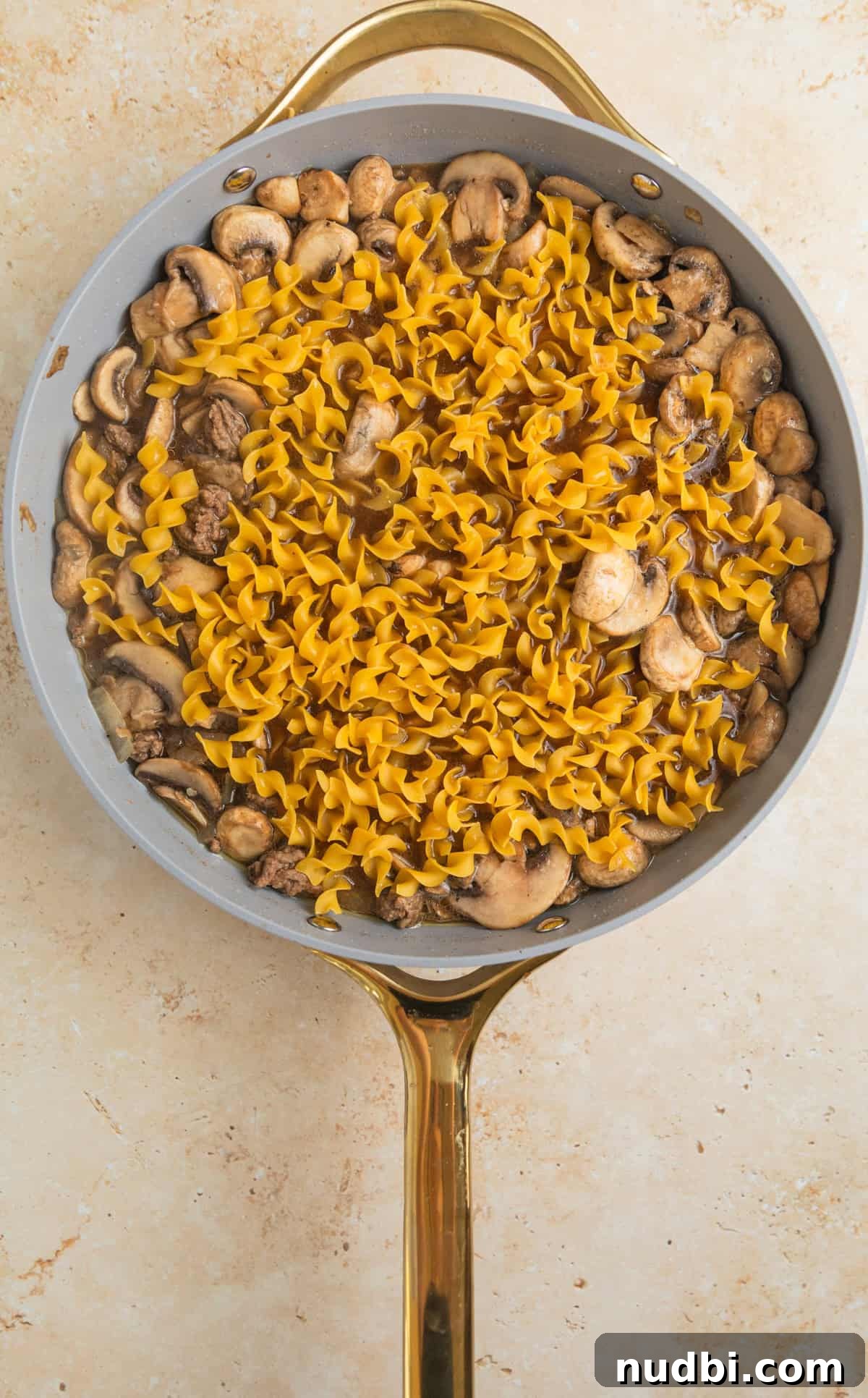 Creamy One-Pot Ground Beef Stroganoff Recipe 7 Wide egg noodles added to skillet with ground beef stroganoff.