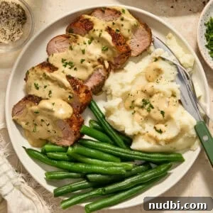 Juicy Pork Tenderloin with Creamy Mustard Sauce receta 11 Plate with pork tenderloin topped with mustard sauce and parsley.