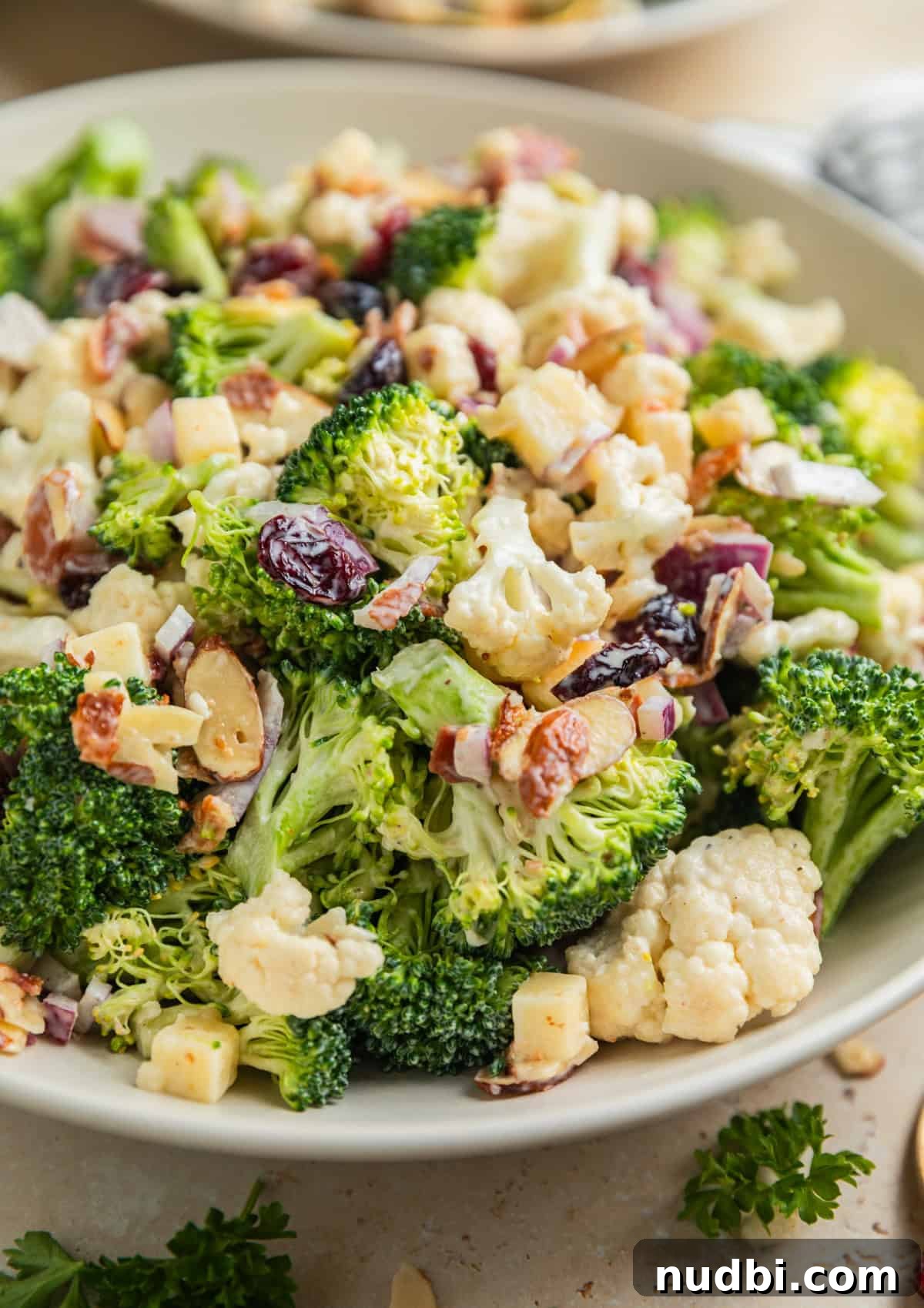 Crunchy Broccoli and Cauliflower Salad with Lemon-Dill Dressing 2 Broccoli cauliflower salad with cranberries, almonds, cheese and other ingredients in serving bowl.