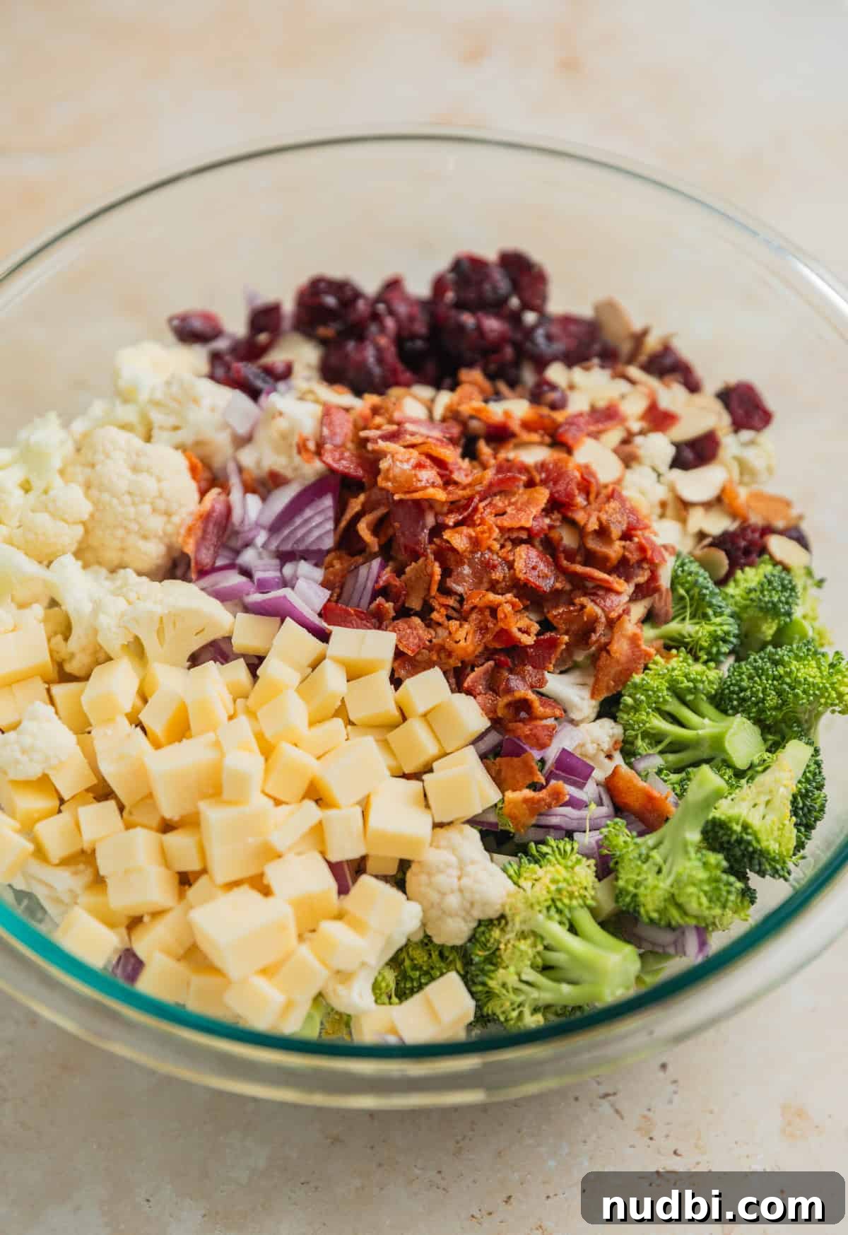 Crunchy Broccoli and Cauliflower Salad with Lemon-Dill Dressing 4 Bite sized broccoli, cauliflower, bacon, cubed cheese, and other ingredients arranged in glass bowl.