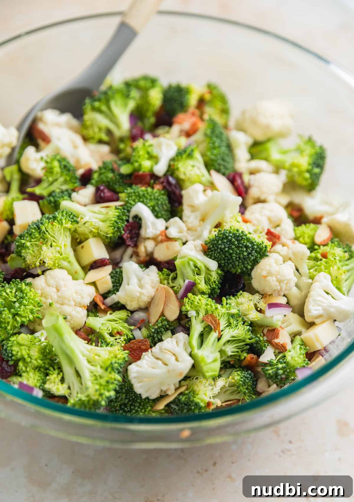 Crunchy Broccoli and Cauliflower Salad with Lemon-Dill Dressing 5 Tossed broccoli cauliflower salad in glass bowl with spoon before adding dressing.