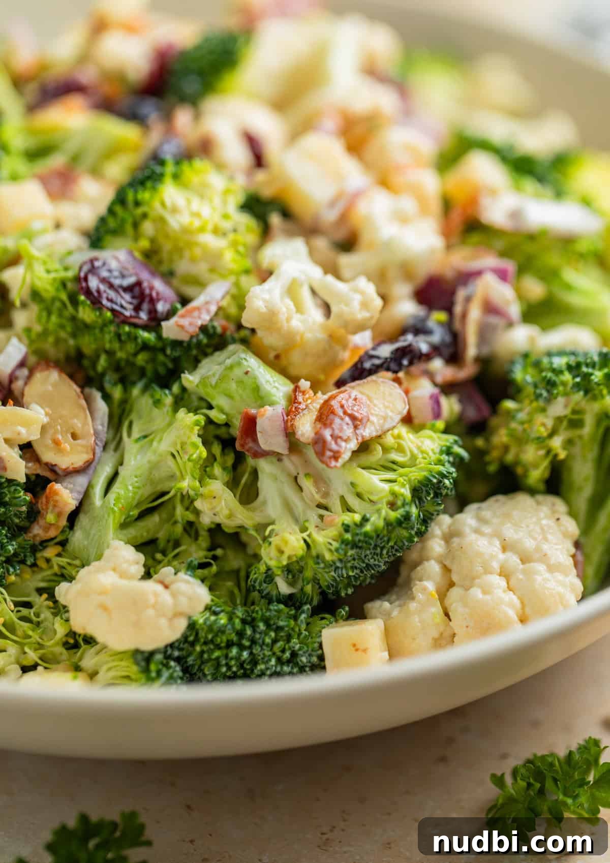 Crunchy Broccoli and Cauliflower Salad with Lemon-Dill Dressing 9 Serving dish with salad topped with chopped bacon, cranberries, almonds and more.