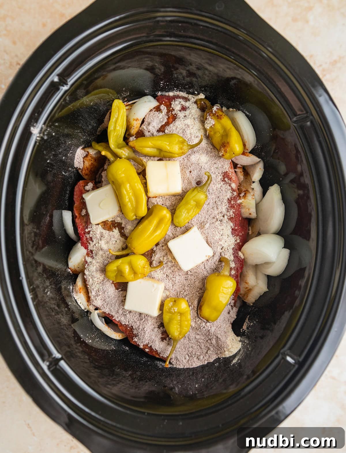 Mississippi Pot Roast in a Slow Cooker: Tender, Flavorful Recipe 5 Chuck roast topped with seasoning, butter and peppers in crock pot.