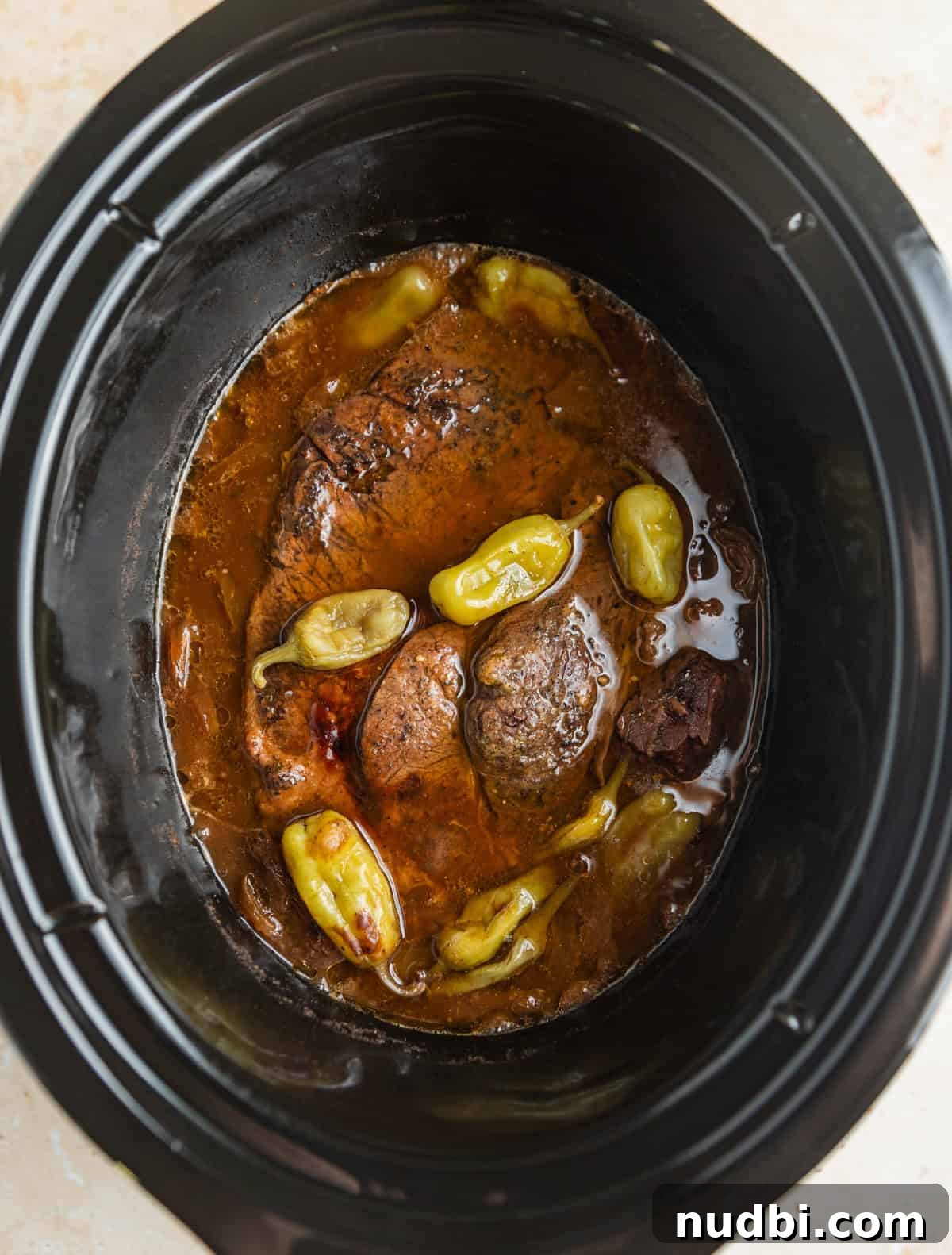 Mississippi Pot Roast in a Slow Cooker: Tender, Flavorful Recipe 6 Cooked pot roast in slow cooker pot with pepperoncinis.