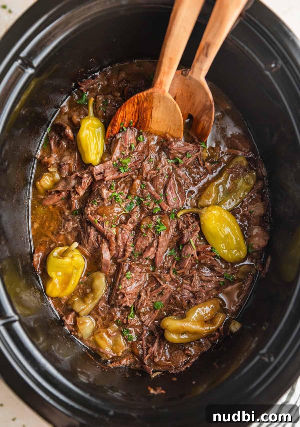 Mississippi Pot Roast in a Slow Cooker: Tender, Flavorful Recipe 7 Crock pot Mississippi pot roast in crockpot with spoons.