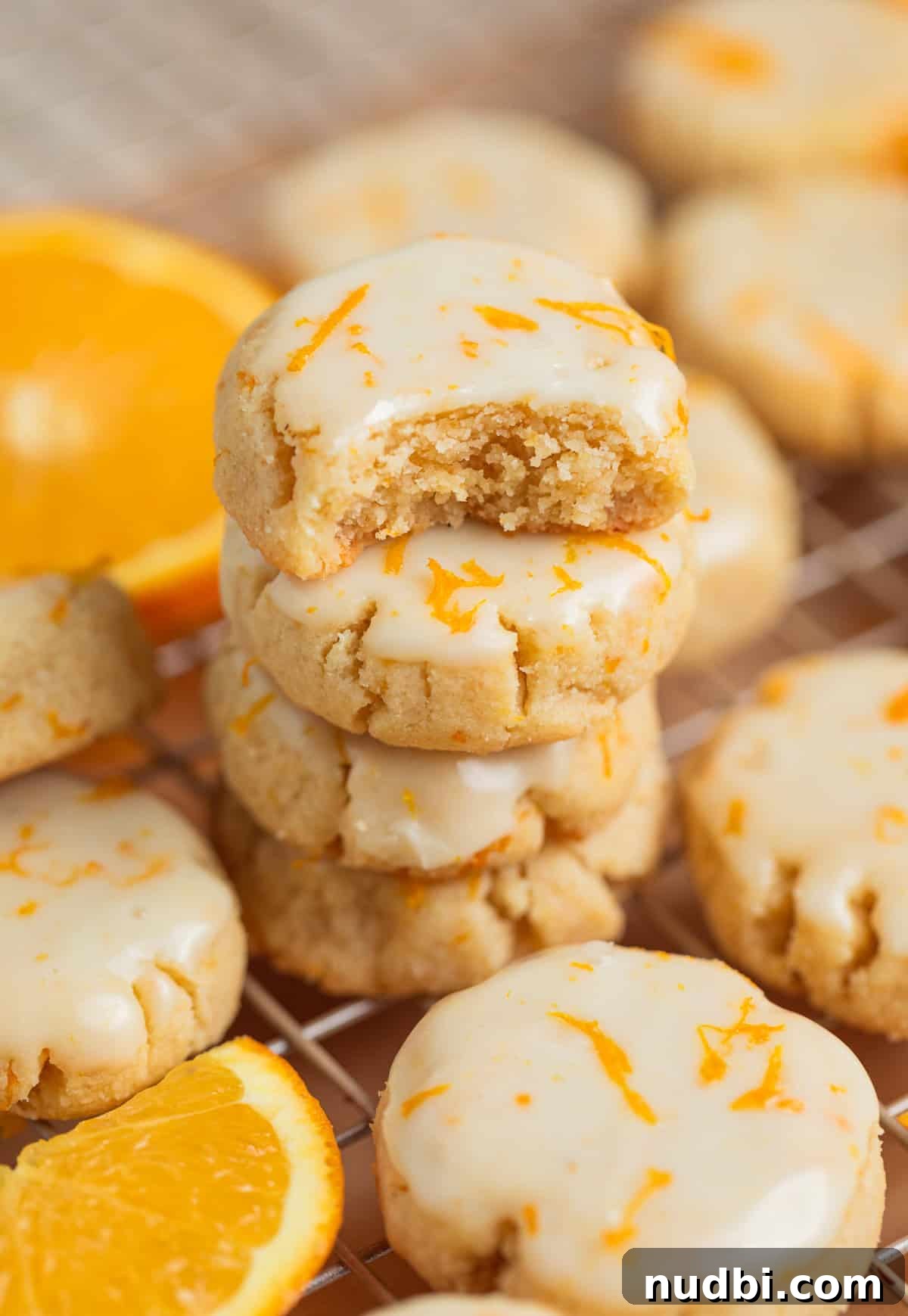 Almond Flour Orange Cookies Recipe — Light Citrus Cookie Guide 2 Stack of iced orange almond flour cookies with bite taken out of top cookie.