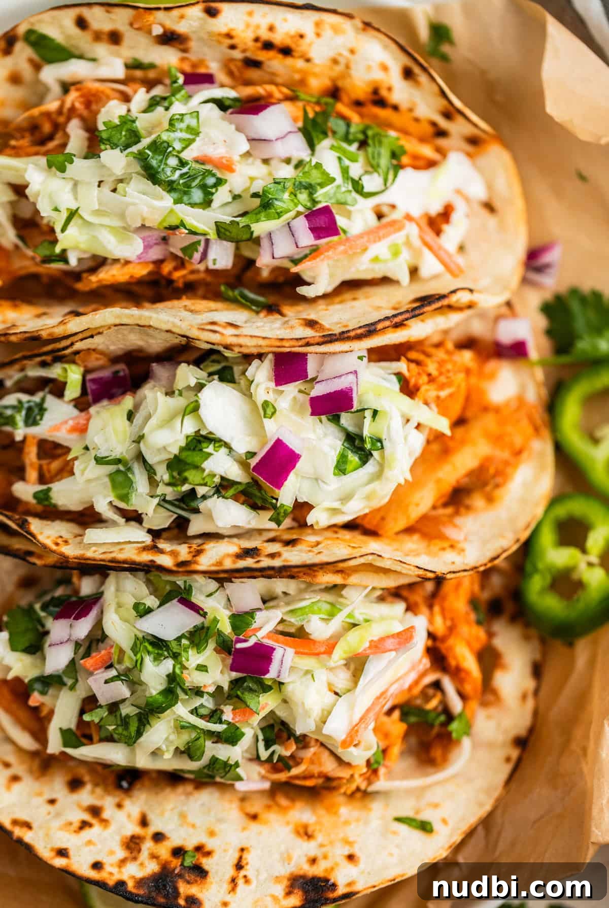 Slow Cooker BBQ Chicken Tacos with Crunchy Lime Slaw 2 Crockpot bbq chicken tacos lined up and topped with slaw.